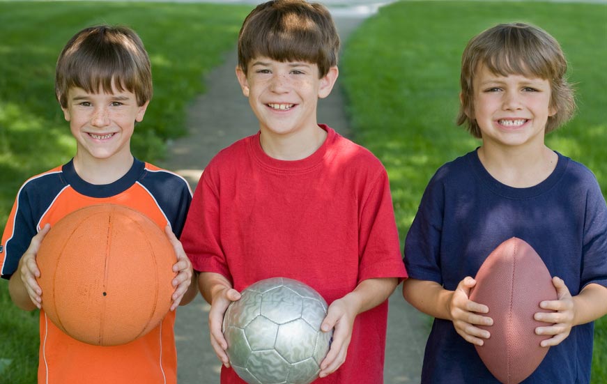 boys holding different sports equipment